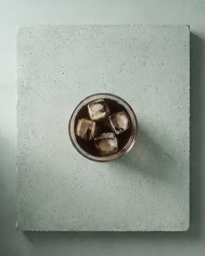 Vaso de cold brew con hielo, visto desde arriba sobre hormigón (imagen generada con IA)
