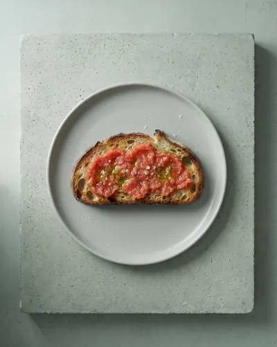 Tostada de masa madre con tomate rallado, vista desde arriba sobre hormigón (imagen generada con IA)